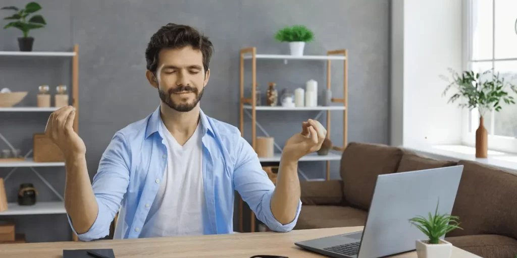 In this photo a man is meditating while doing his office work.